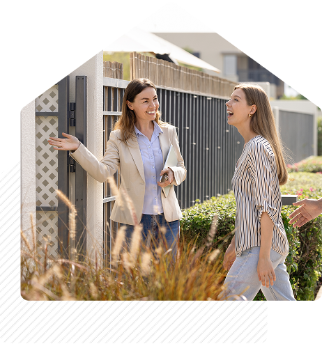 Real estate agent smiling and greeting clients outside a modern home during a property showing.