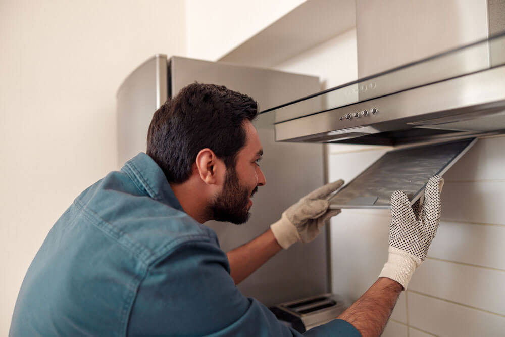 Maintenance man fixing kitchen exhaust