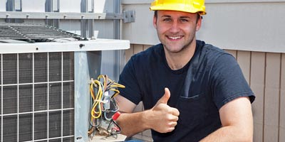 Man in hard hat repairing air conditioner